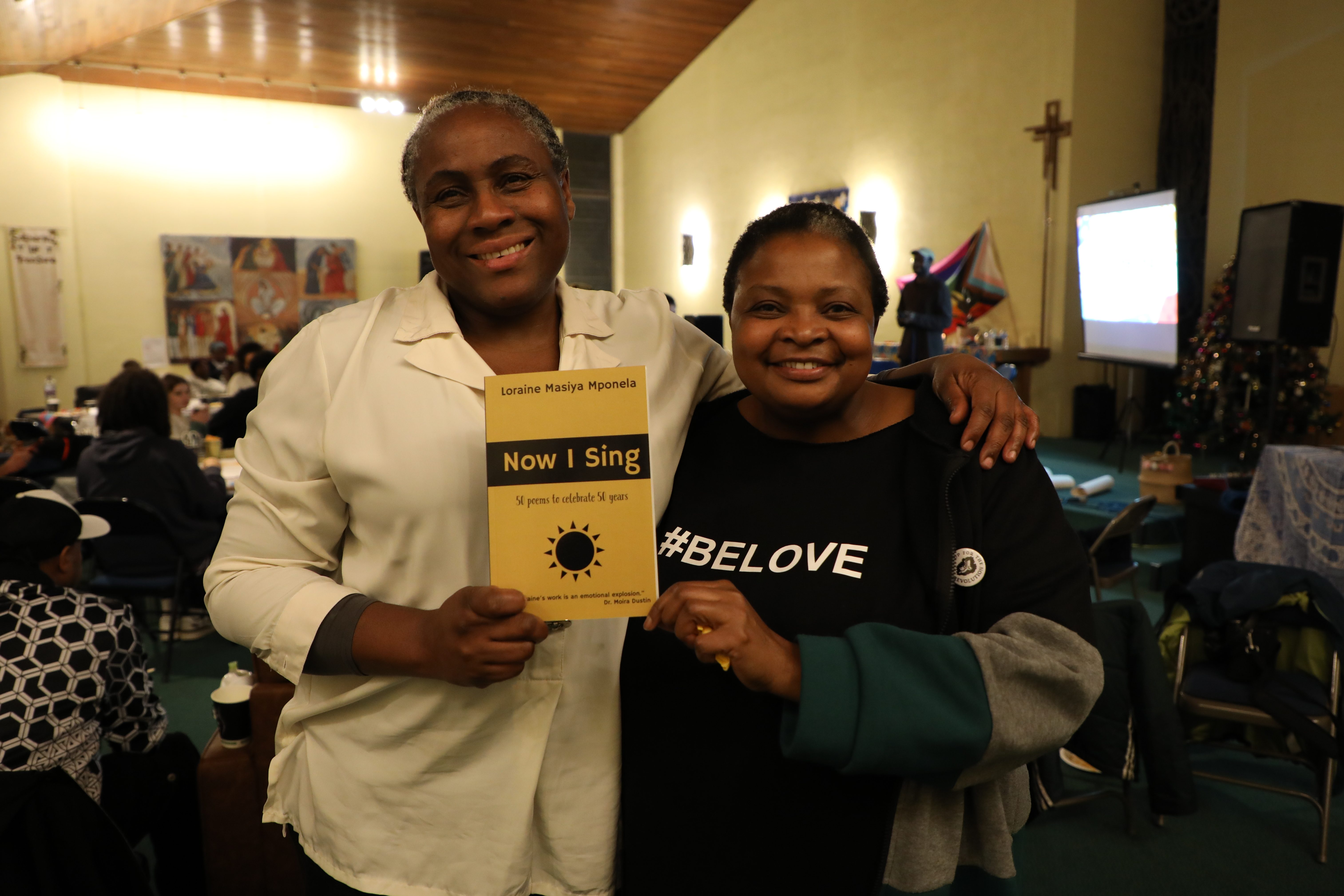 Community members with Now I Sing poetry book